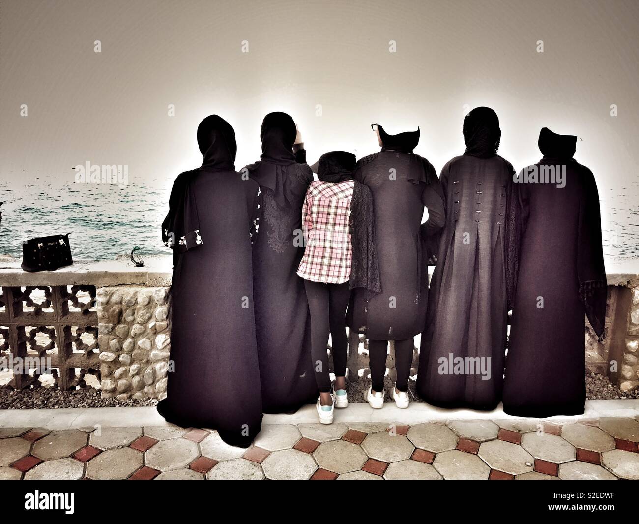 Girls in Black: girls from Oman wearing traditional black Abaya, watching the sea Stock Photo