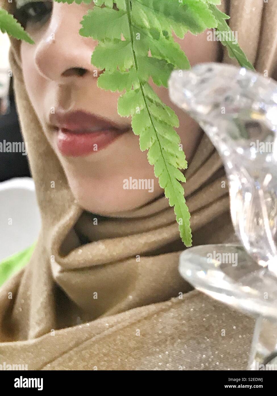 Shy. A Muslim girl hiding behind a plant - Smartphone Captured Stock Image