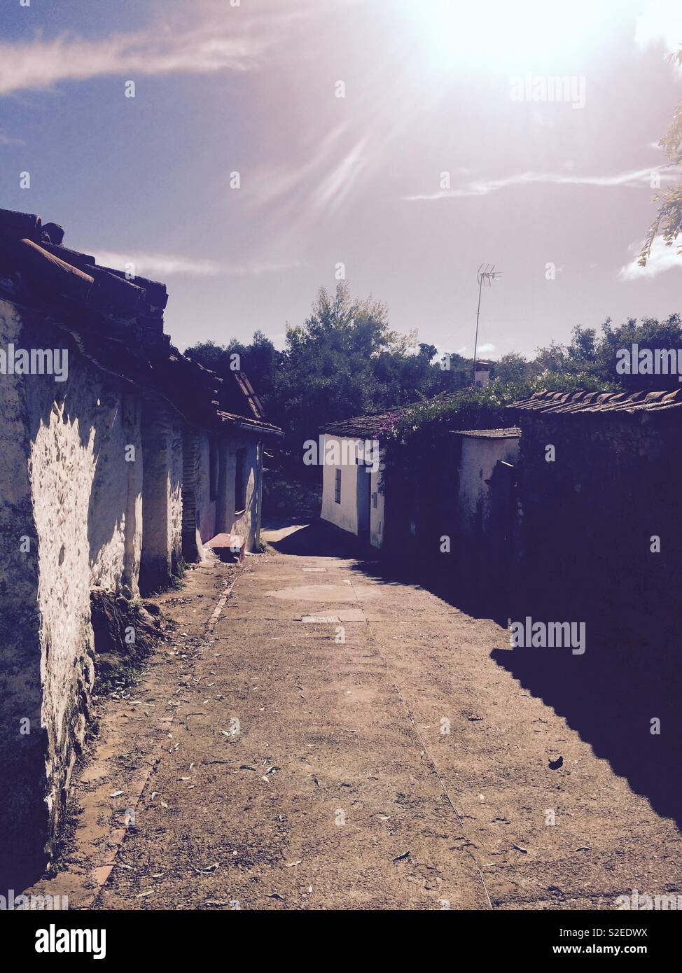 Small cobbled street or lane in El Collado village with Spanish style cottages on a sunny Autumn day in the Sierra de Aracena mountainside in Andalucia Spain Stock Photo