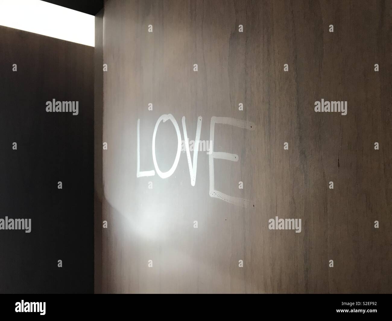 The word “love” written in condensation on a door Stock Photo