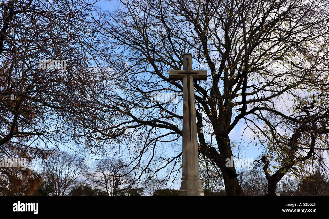 Ornamental stone cross set against trees in the background Stock Photo