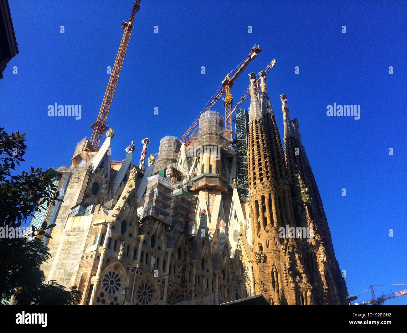 Sagrada Familia basilica architectural details on exterior of building and steeples while under construction with cranes Stock Photo