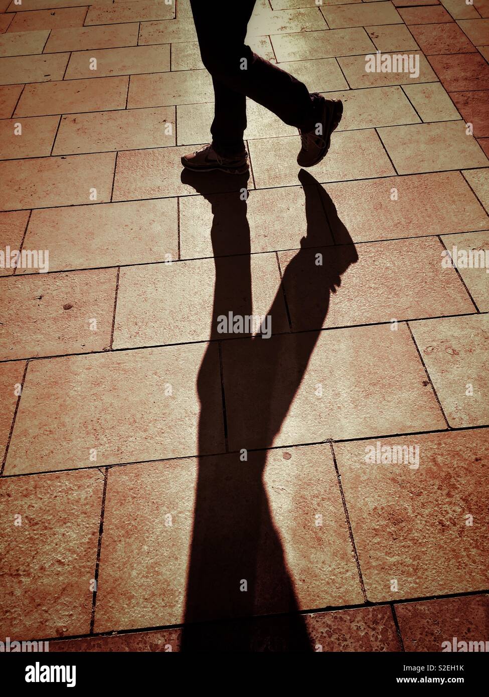 Mans legs and shadows on paving Stock Photo Alamy