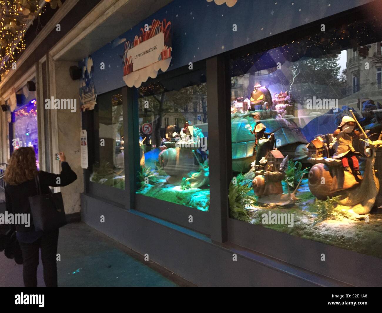 Woman taking photo of Christmas window at Printemps department store, Paris, France Stock Photo