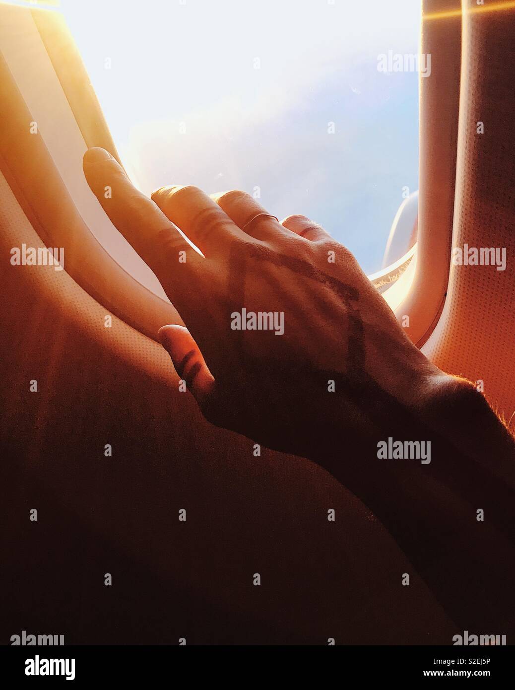 Reach Out and Touch the Sky. A hand with henna tattoo is reaching for the illuminator in an airplane somewhere over Atlantic Ocean, 2017. Hand of photographer. Ring - property of photographer - Smartphone Captured Stock Image