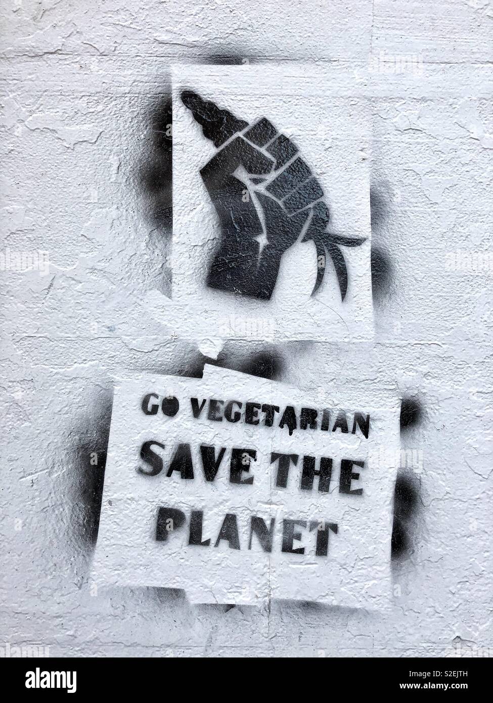 Go vegetarian graffiti stencilled on the wall of a building in Dumfries town centre, Scotland.  It shows a fist holding a carrot instead of a grenade. - Smartphone Captured Stock Image