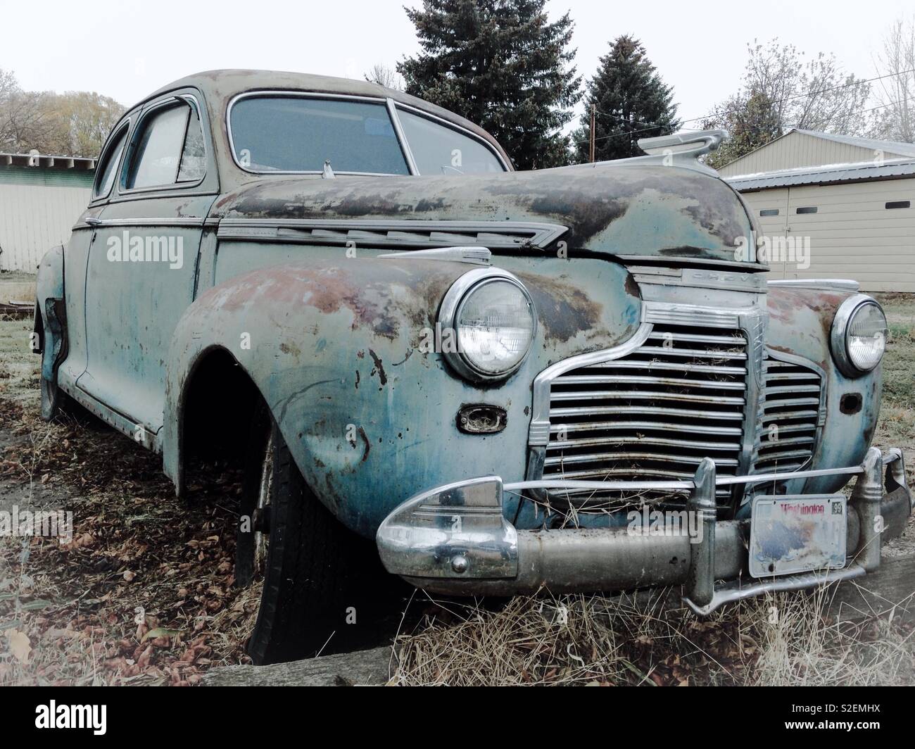 Vintage Rusty gray/blue Chevrolet coupe parked for restoration, from front - Smartphone Captured Stock Image