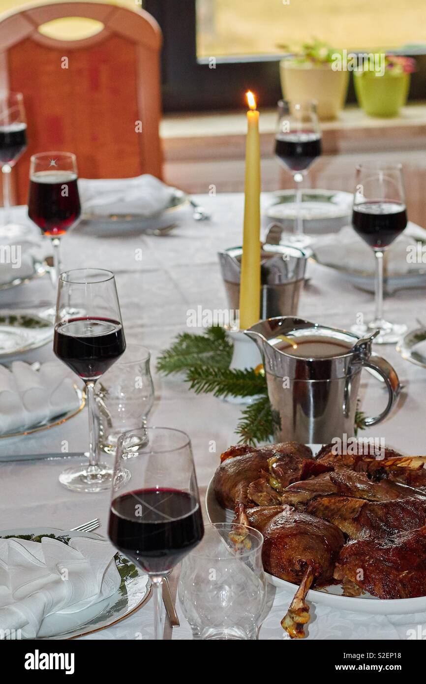 https://c8.alamy.com/comp/S2EP18/a-festively-set-dining-table-at-christmas-time-with-geese-or-duck-legs-in-the-foreground-filled-red-wine-glasses-a-burning-candle-napkins-and-roast-soap-in-a-jug-S2EP18.jpg