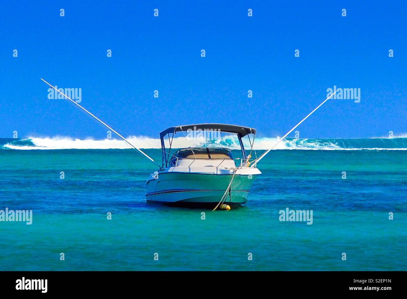 a deep sea fishing boat anchors in the turquoise water off the