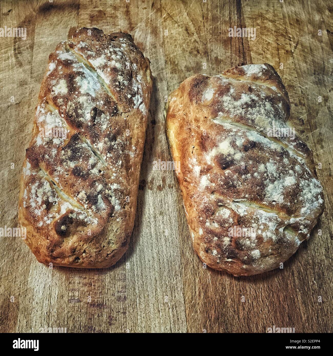 Two loaves of home made bread on a wooden cutting board. - Smartphone Captured Stock Image