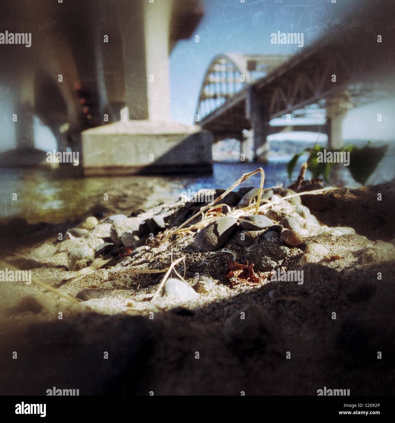 Tinge of grunge in photo of sand and rocks under the I-90 bridge at Lake Washington, Seattle - Smartphone Captured Stock Image