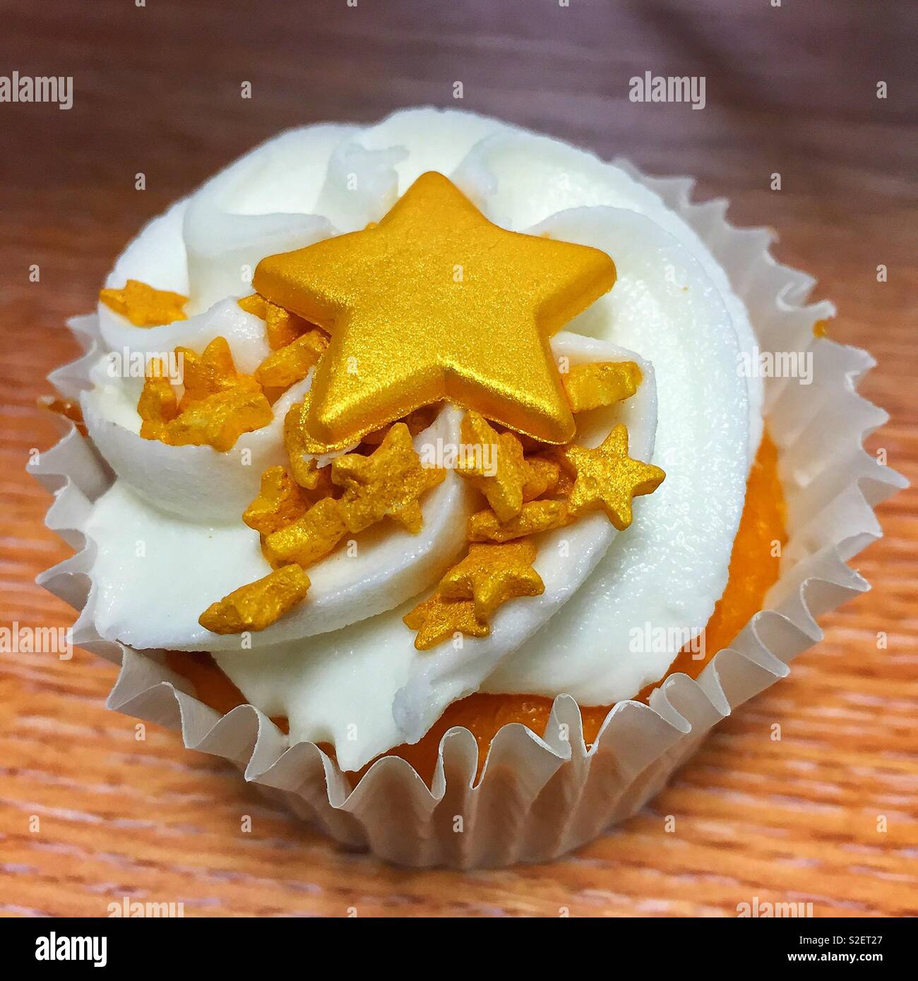 A single cupcake with gold stars on top of its white icing Stock Photo ...