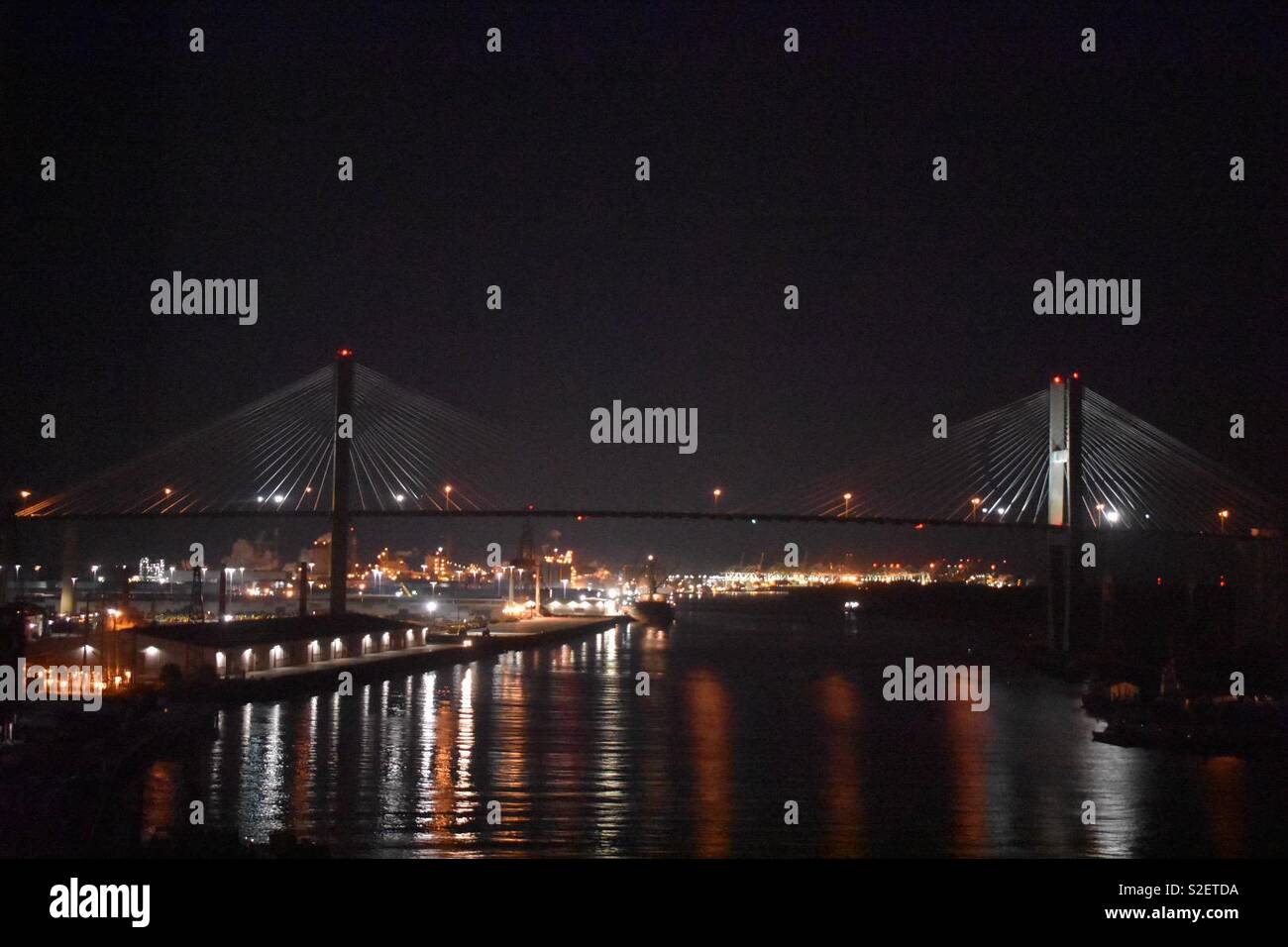 Suspension bridge over the Savannah River at night with the Savannah port in the background Stock Photo