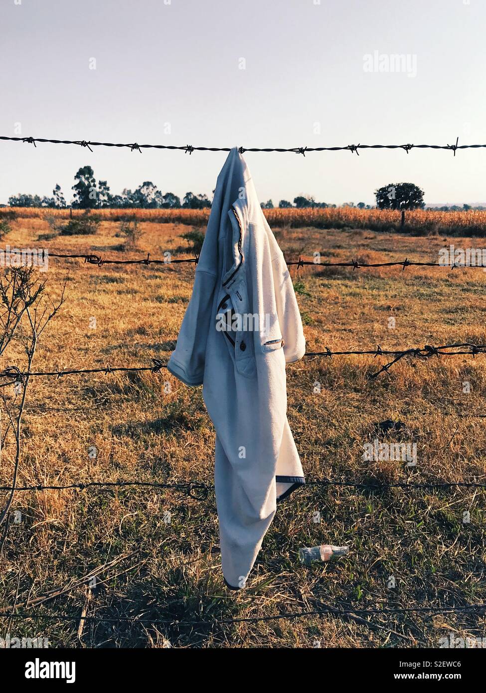 Inhumane Borders (in color). Preused white polo shirt stuck in a barbed wire. Depiction of dangers of crossing borders. Shot near Tepatitlán de Morelos, Jalisco, Mexico. 1st January 2018 - Smartphone Captured Stock Image