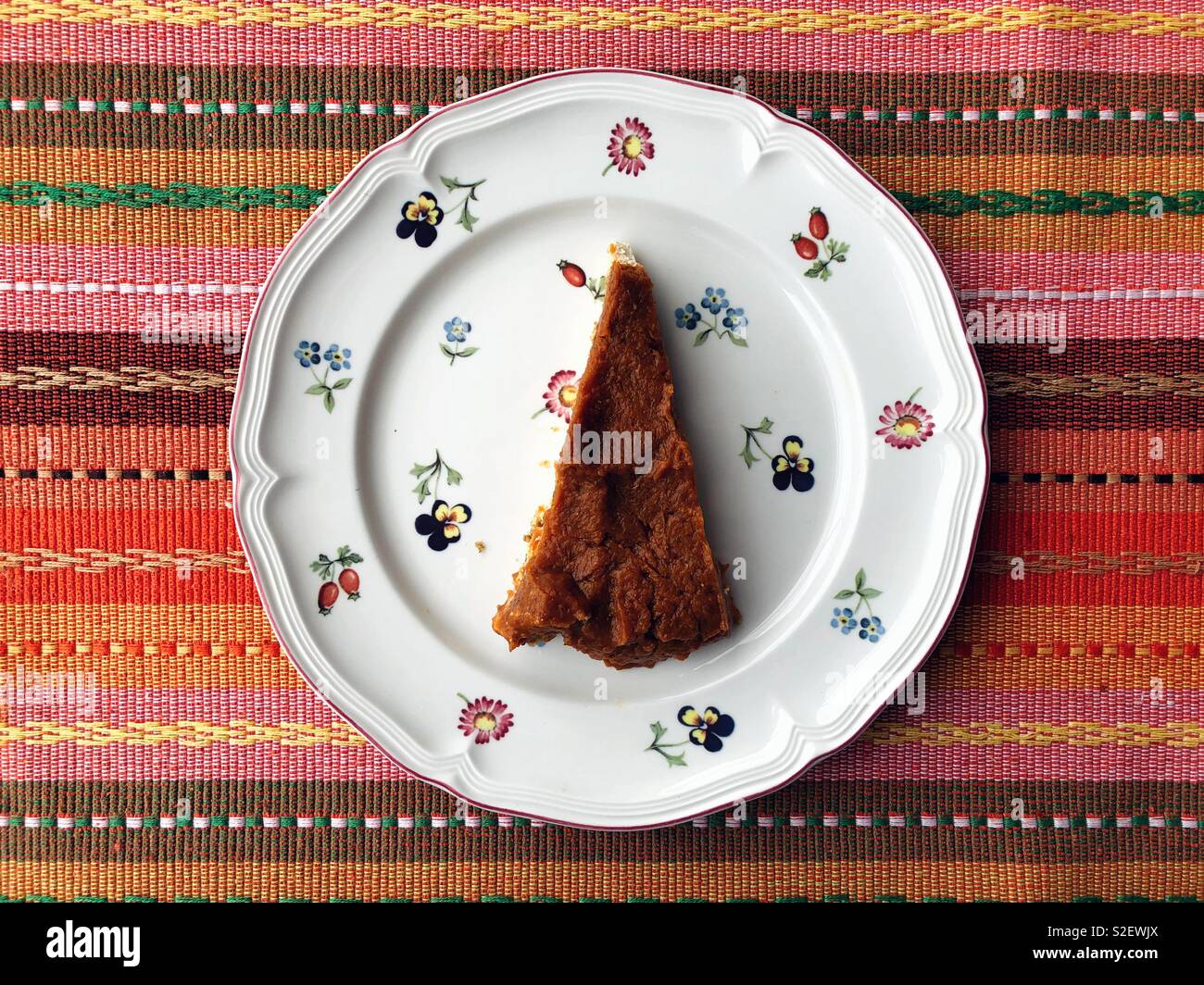 Vegan pumpkin cheesecake on cute plate and stripy woven placemat for Thanksgiving dinner Stock Photo