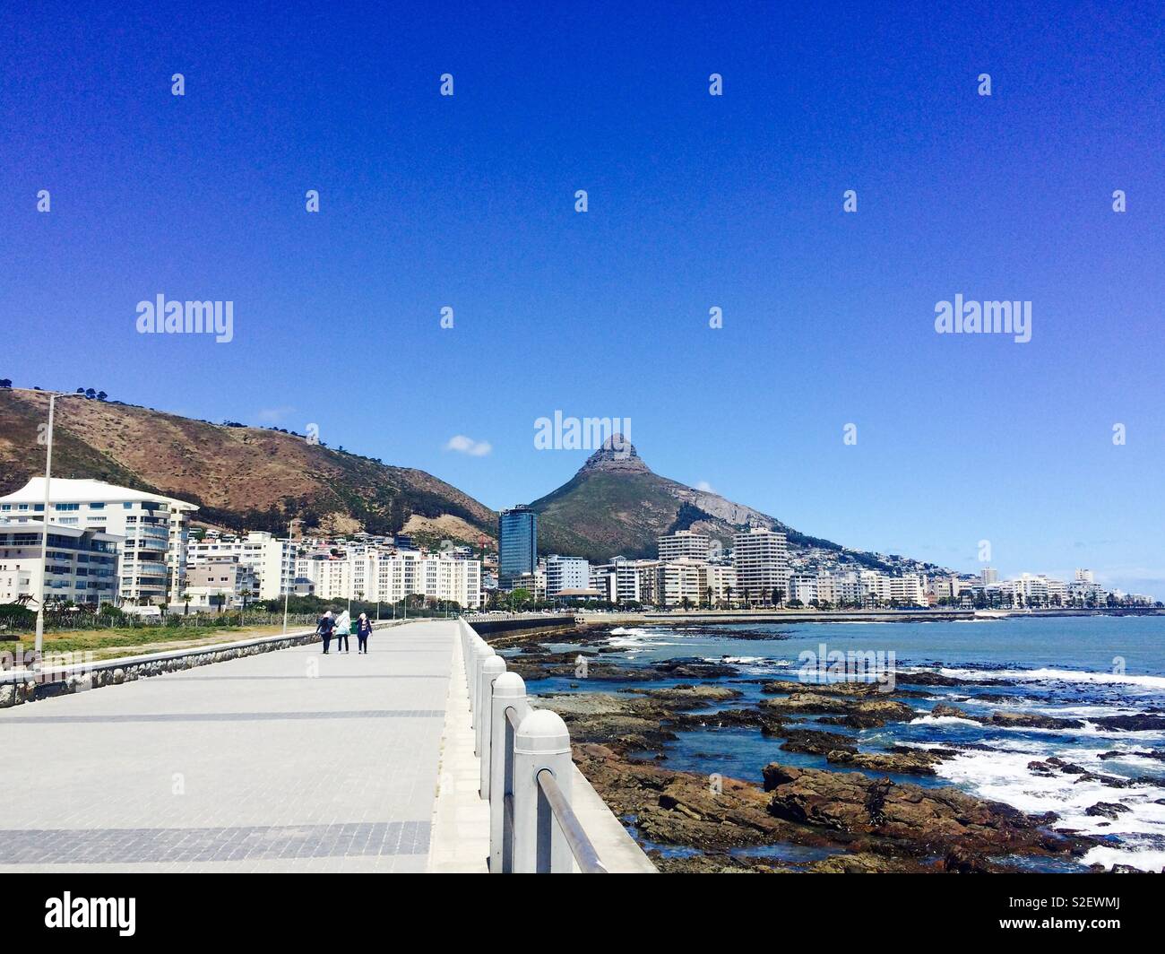 Promenade or walkway along the Atlantic Ocean coastline of Mouille Point looking toward Sea Point and Lion's Head in Cape Town, South Africa on a sunny Summer's day Stock Photo