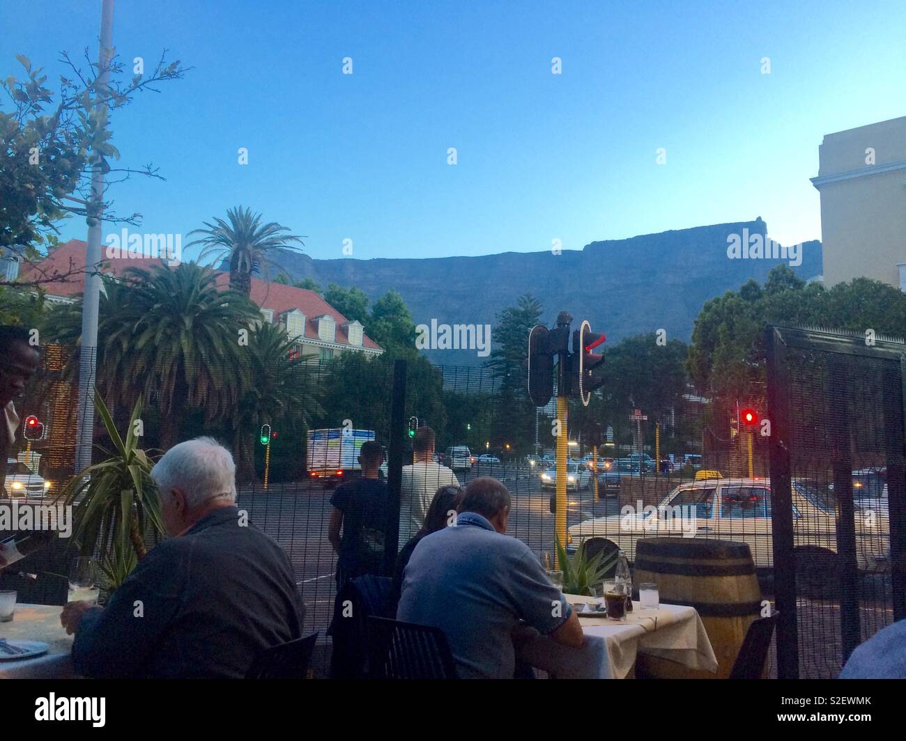 Scenic evening view of Table Mountain from outdoor city restaurant with diners seated at tables in Summer Cape Town, South Africa - Smartphone Captured Stock Image
