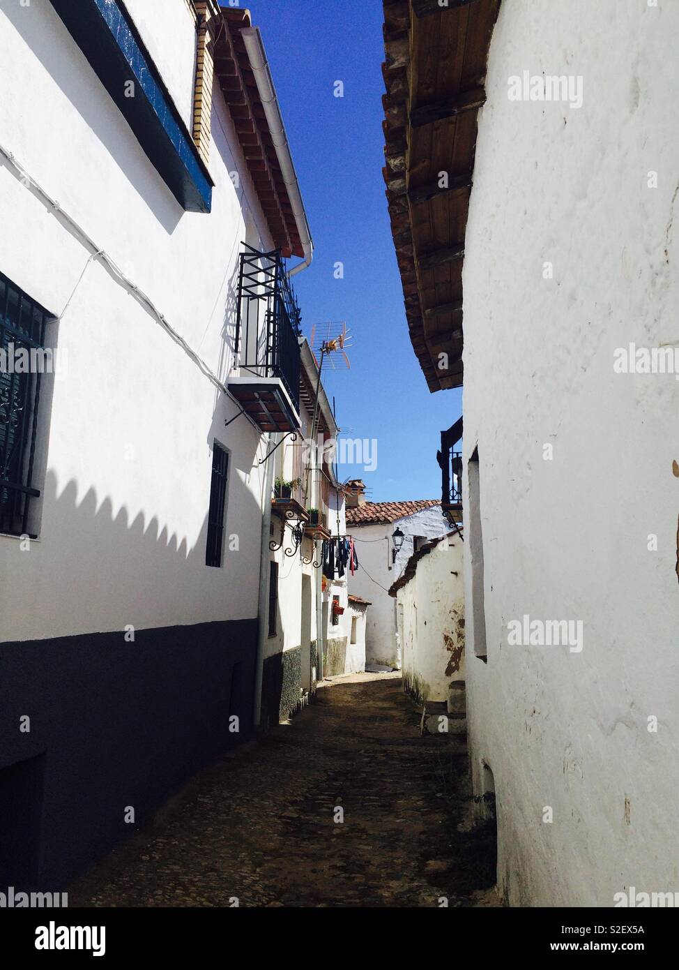 Narrow village cobbled lane between Spanish style houses in Alájar Andalucia Spain Stock Photo