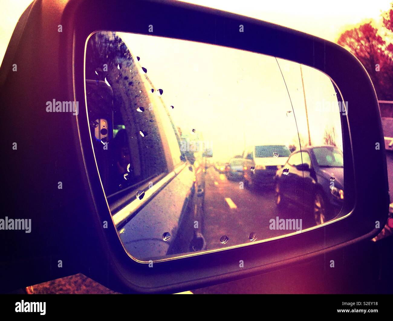 Looking back at stationary traffic in a car wing mirror. - Smartphone Captured Stock Image