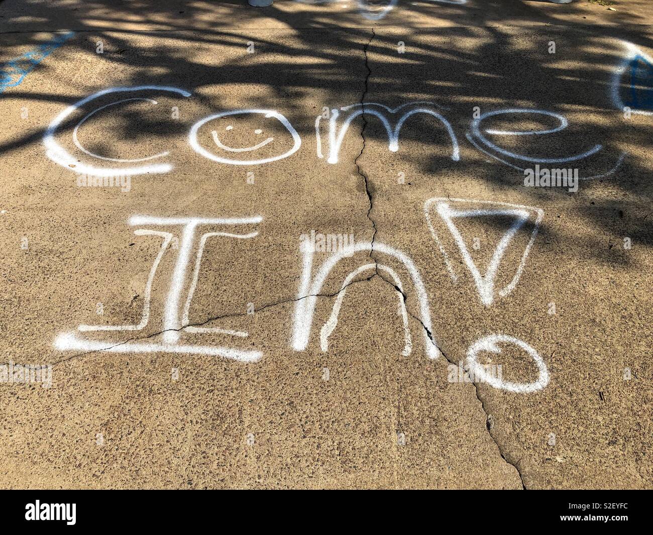 Come In graffitied on the sidewalk. Stock Photo
