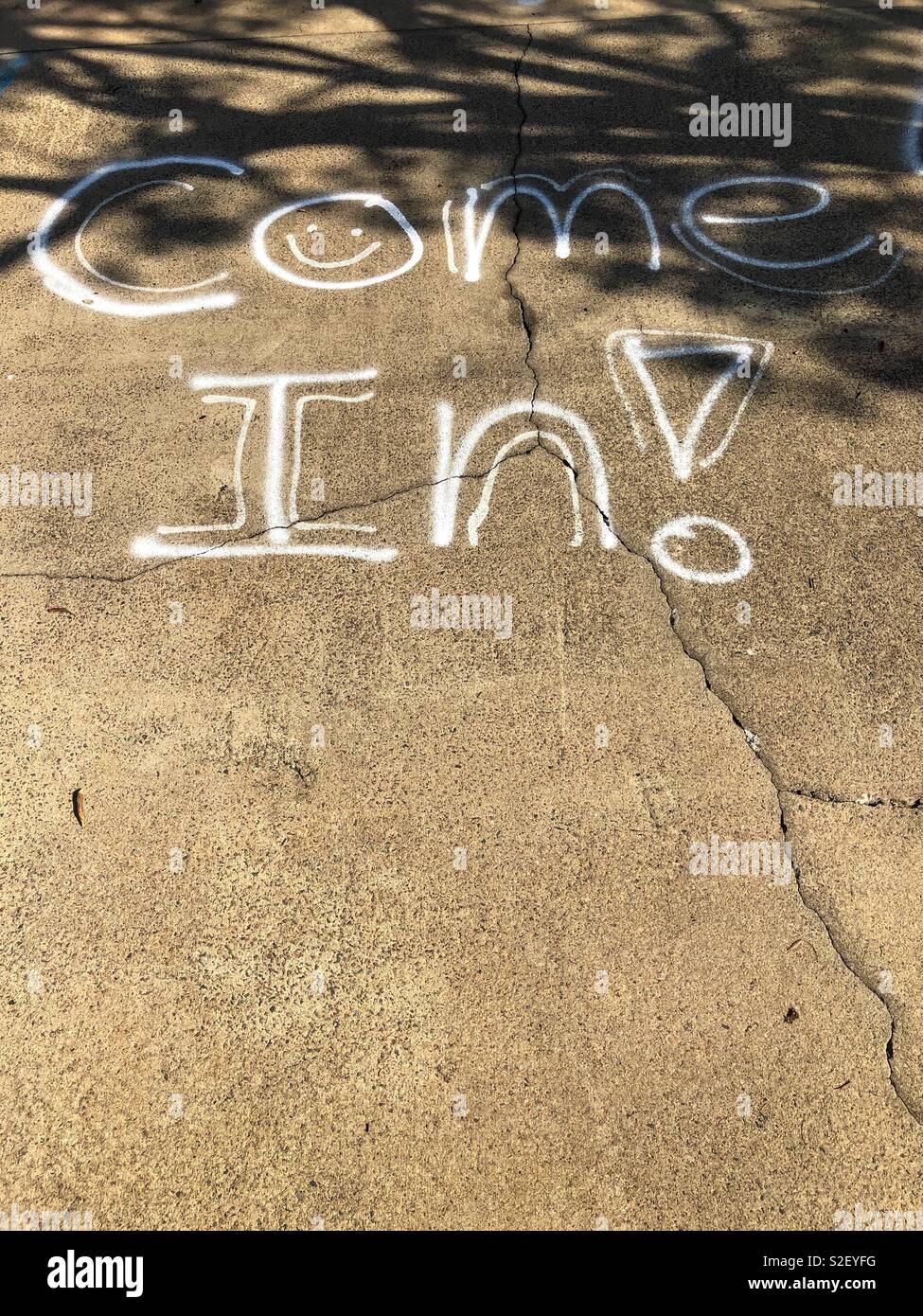Come In graffitied on the footpath. Stock Photo