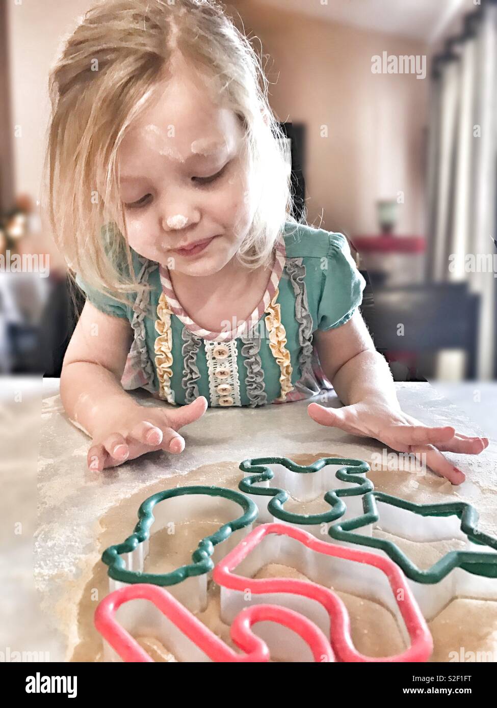 Little girl with flour on her face while making Christmas cookies Stock Photo