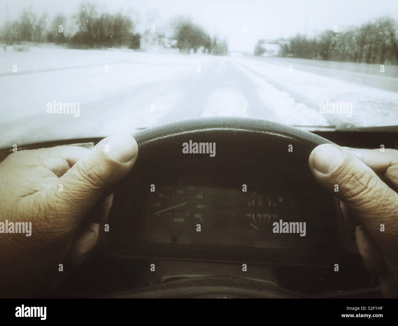 Elderly man hands on a steering on a winter road Stock Photo