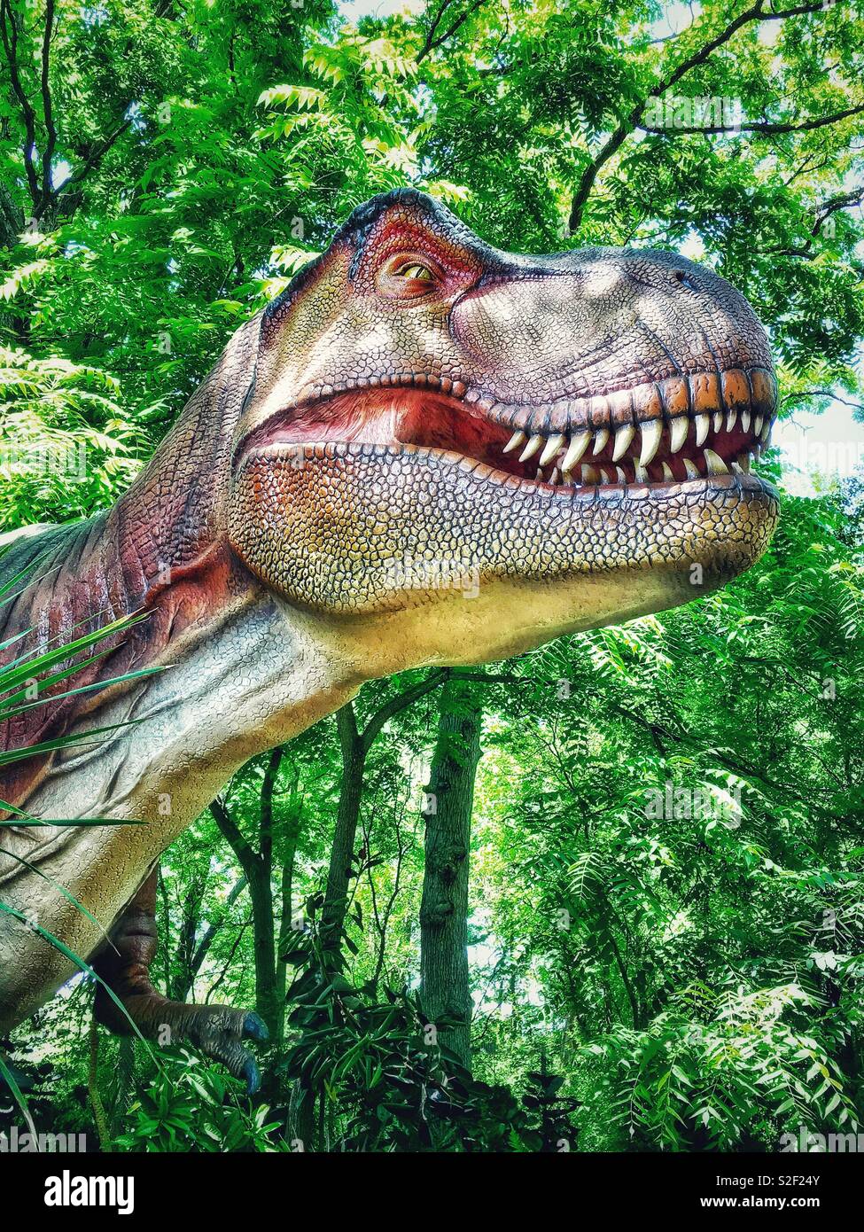 Color enhanced Robotic Tyrannosaurus Rex smiling in foliage Stock Photo