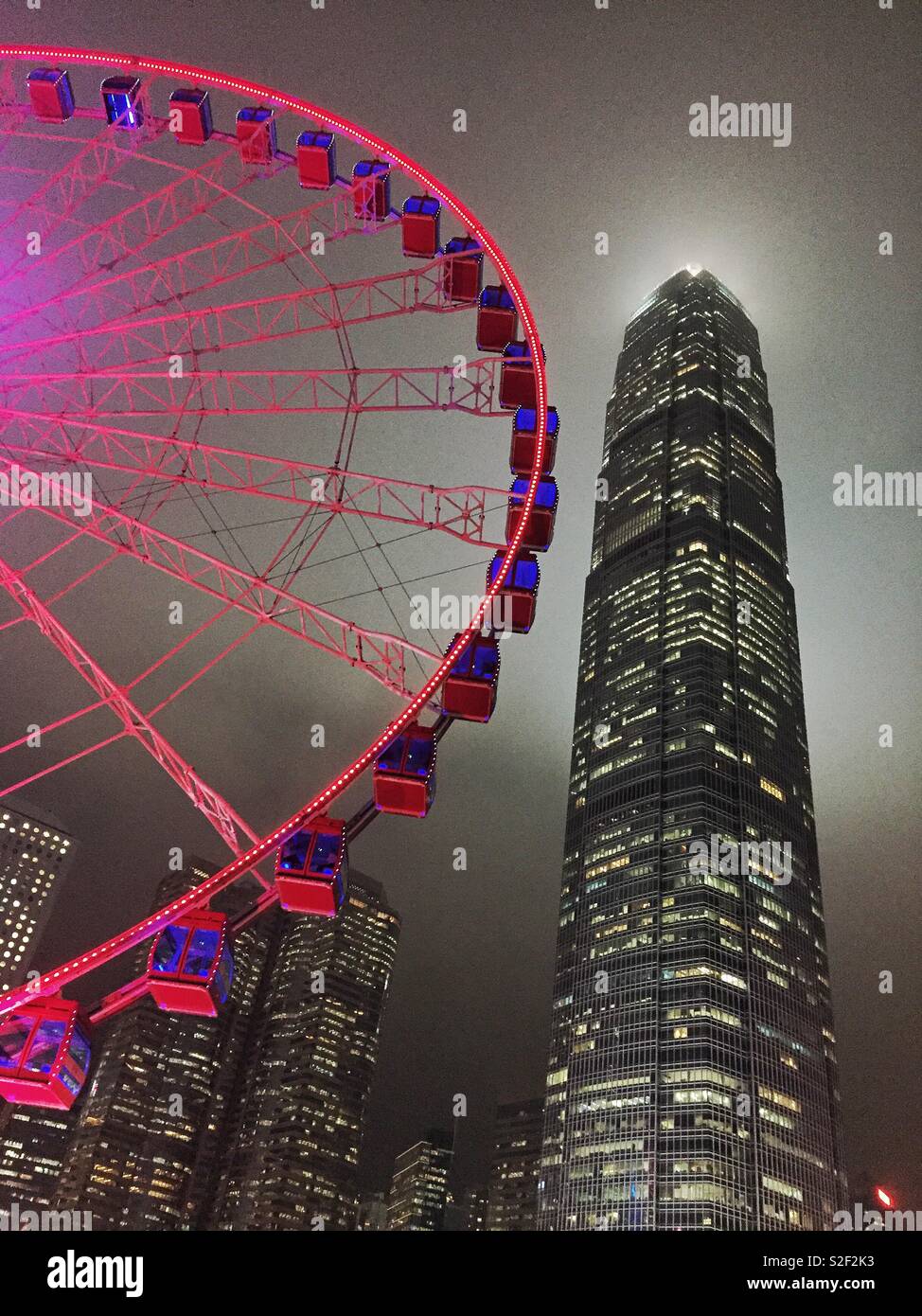 The Hong Kong Observation Wheel at the Central waterfront at night, with 2ifc, Hong Kong Island's tallest skyscraper - Smartphone Captured Stock Image