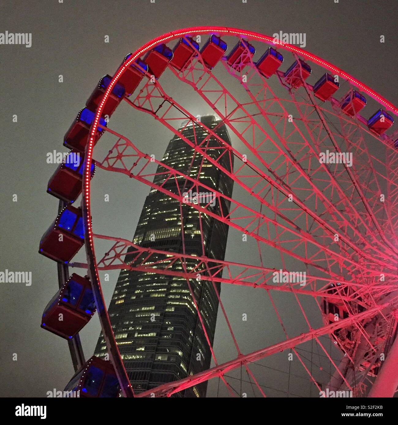 The Hong Kong Observation Wheel at the Central waterfront at night, with 2ifc, Hong Kong Island's tallest skyscraper - Smartphone Captured Stock Image