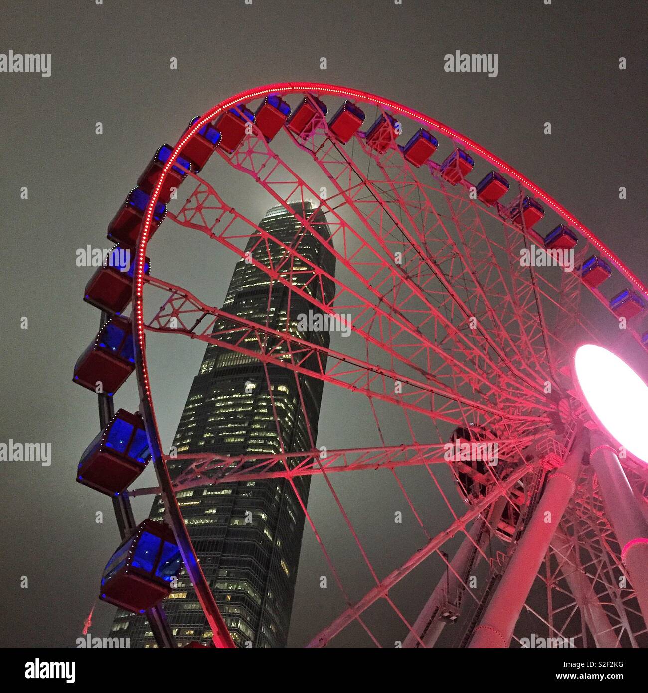 The Hong Kong Observation Wheel at the Central waterfront at night, with 2ifc, Hong Kong Island's tallest skyscraper - Smartphone Captured Stock Image