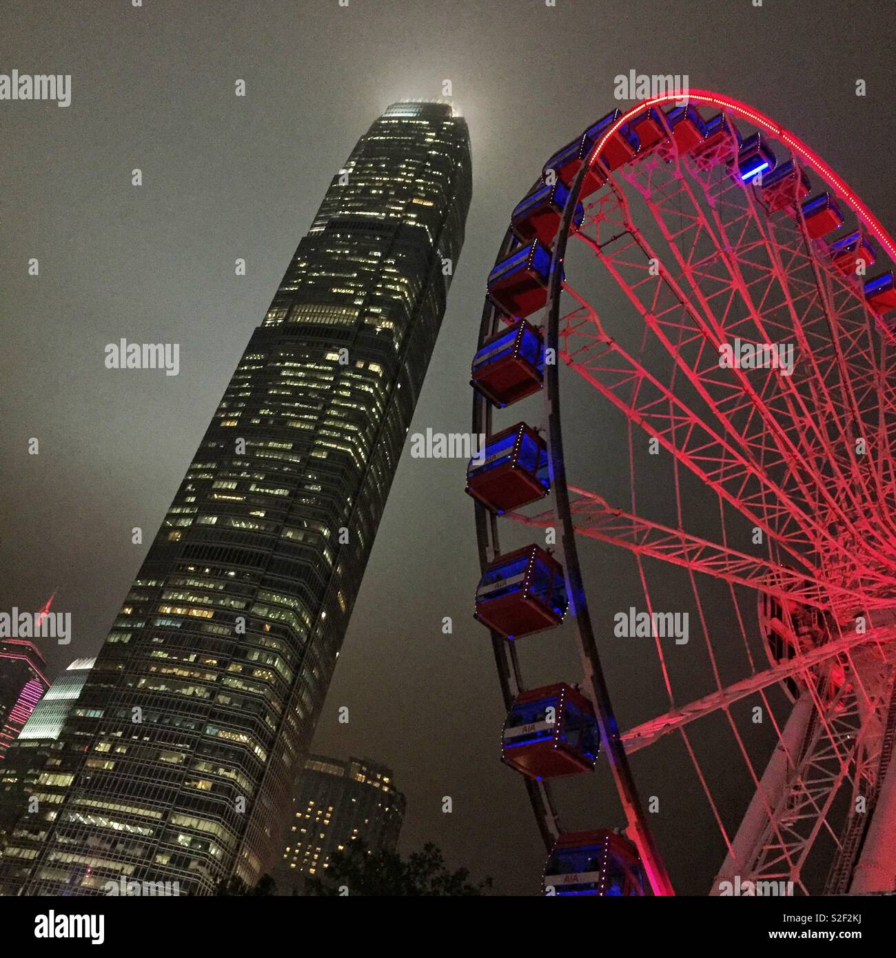 The Hong Kong Observation Wheel at the Central waterfront at night, with 2ifc, Hong Kong Island's tallest skyscraper - Smartphone Captured Stock Image