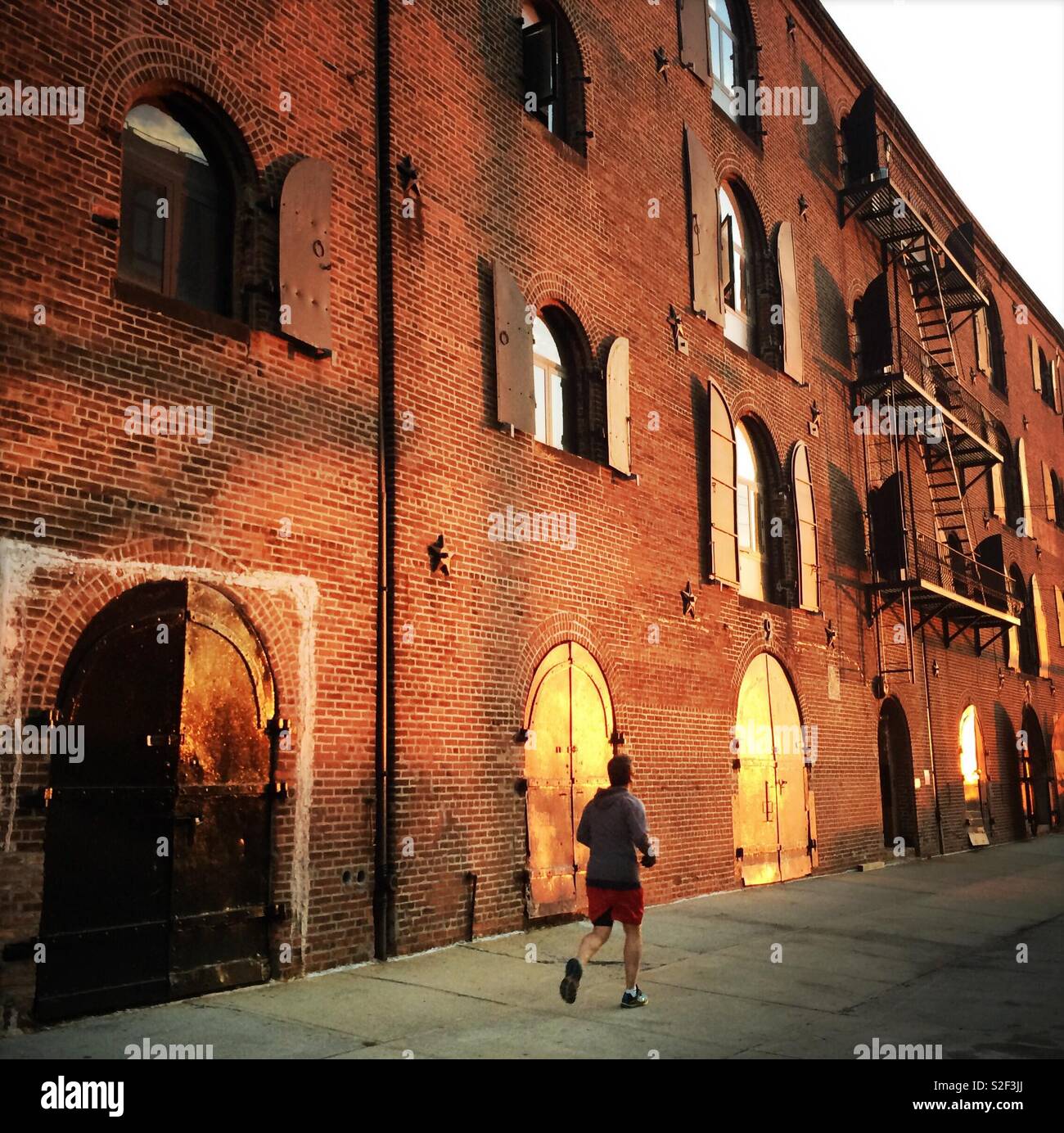 Man running along warehouses at sunset, Red Hook Brooklyn, USA Stock Photo