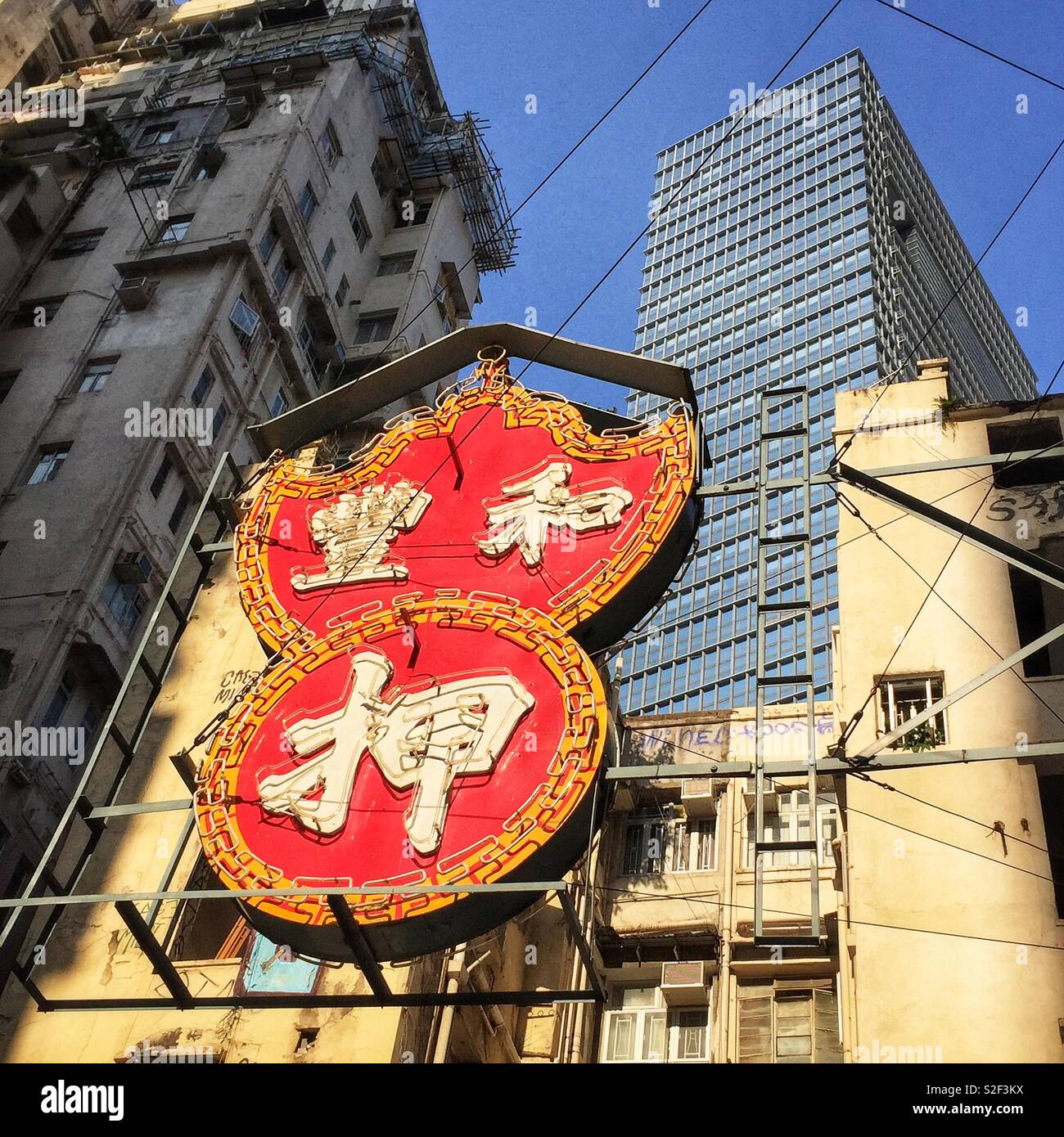 A sign for a pawnbroker seen against a mix of old-style walk-up tenements and a modern high-rise commercial building in Causeway Bay, Hong Kong Island - Smartphone Captured Stock Image