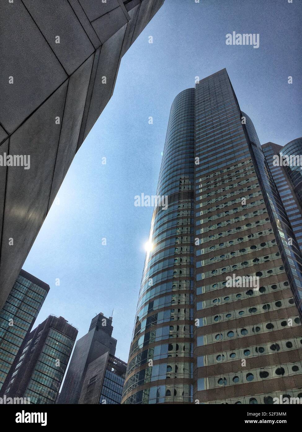 The distinctive round windows of Jardine House reflected in the facade of One Exchange Square, Central, Hong Kong Island - Smartphone Captured Stock Image