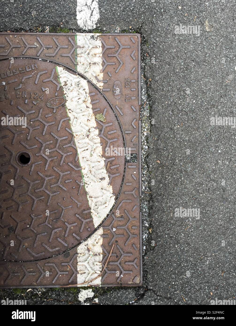Line on manhole cover not straight. Stock Photo