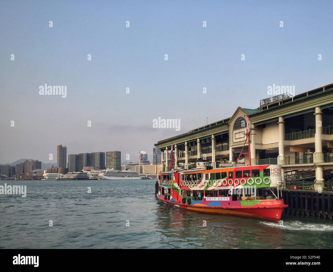 An iconic Star ferry, painted in the livery of Brand Hong Kong, departs from Central Pier 7 to cross Victoria Harbour to Tsim Sha Tsui in Kowloon - Smartphone Captured Stock Image