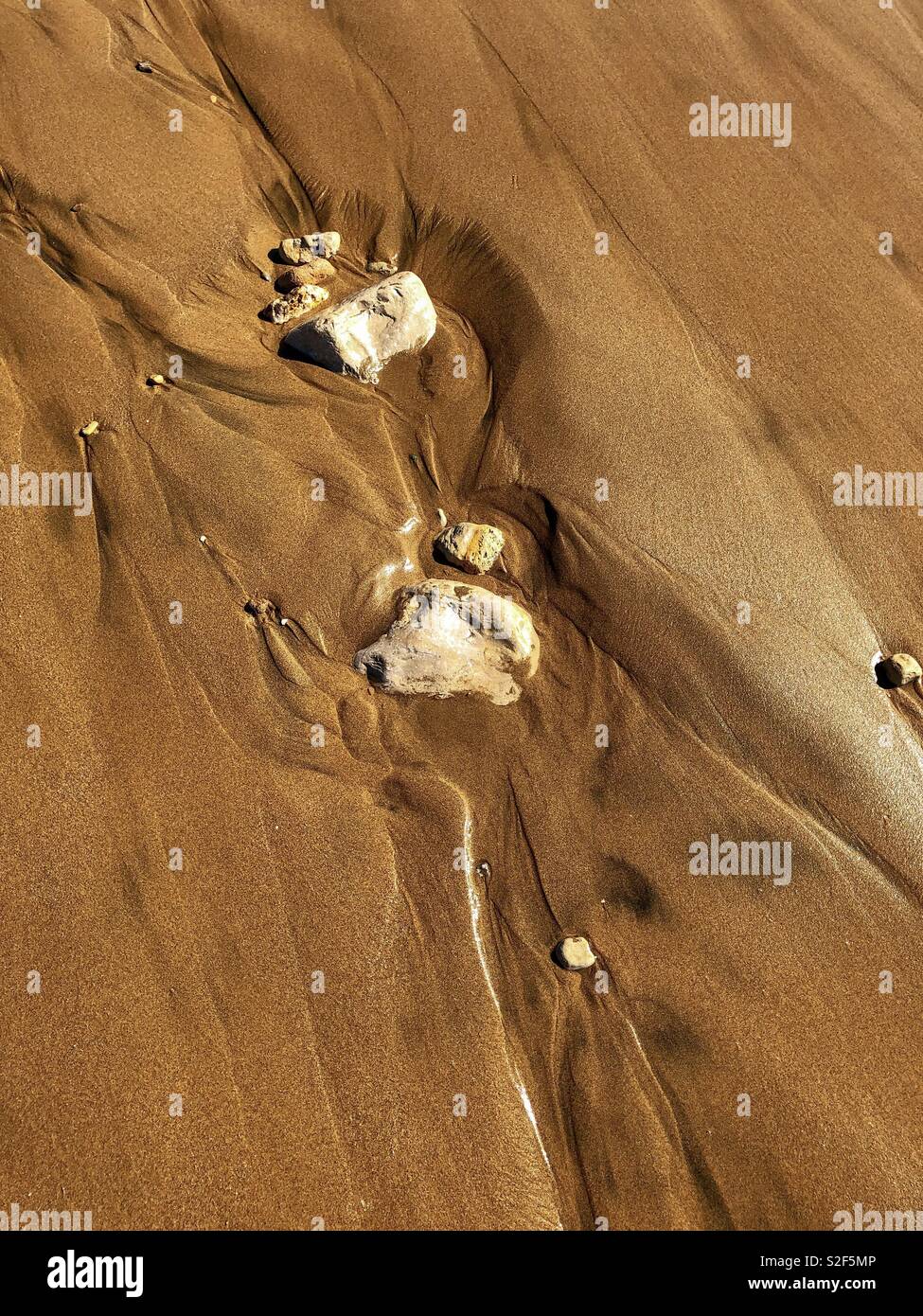 Sand shapes and water channels created by stones and the Atlantic Ocean - Smartphone Captured Stock Image