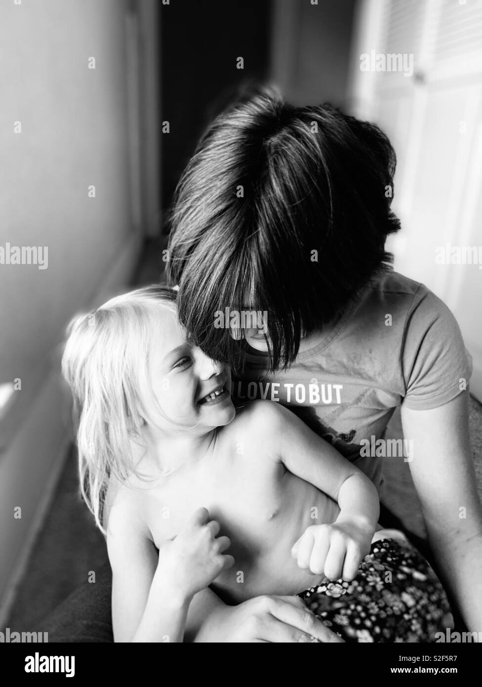 Two sisters sharing a happy moment smiling at home. - Smartphone Captured Stock Image