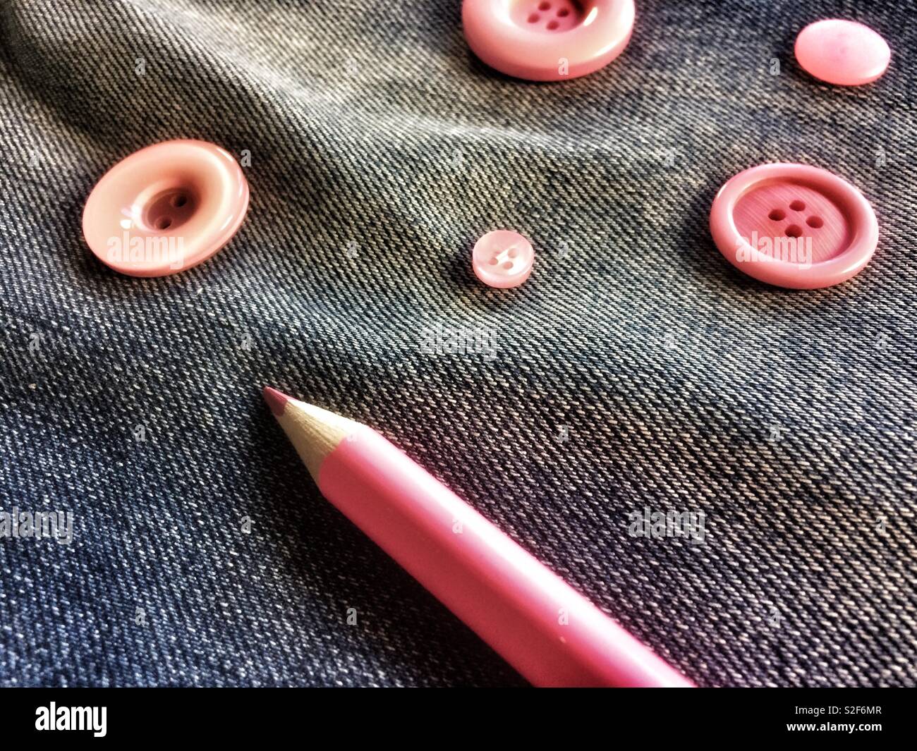 Pink buttons and pencil on denim - Smartphone Captured Stock Image