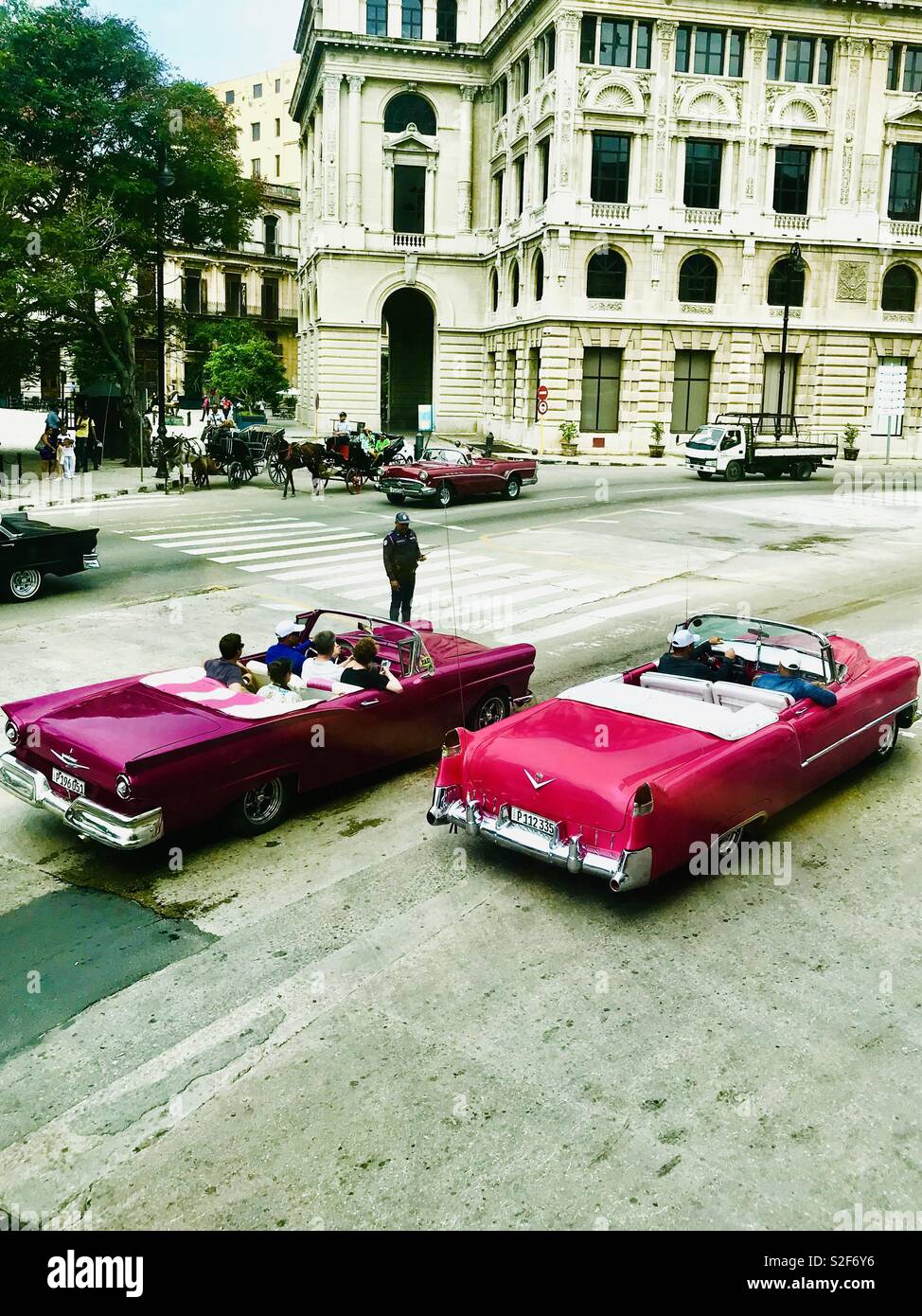 Classic Cadillac Cars cruising with their rooftops down around the streets of Havana Cuba Stock Photo
