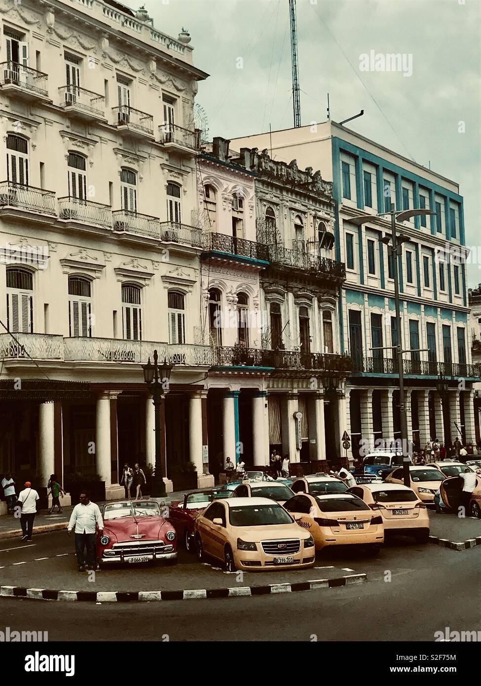 Classic cars and taxi cabs parked outside some beautiful colonial buildings in the centre of Havana Cuba Stock Photo