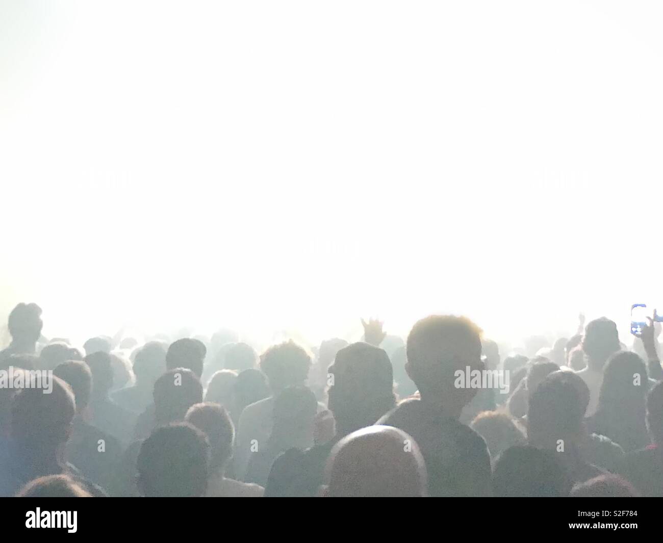Many unrecognizable concert fans are shown from behind with a solid, white area for your own text or graphics above. - Smartphone Captured Stock Image