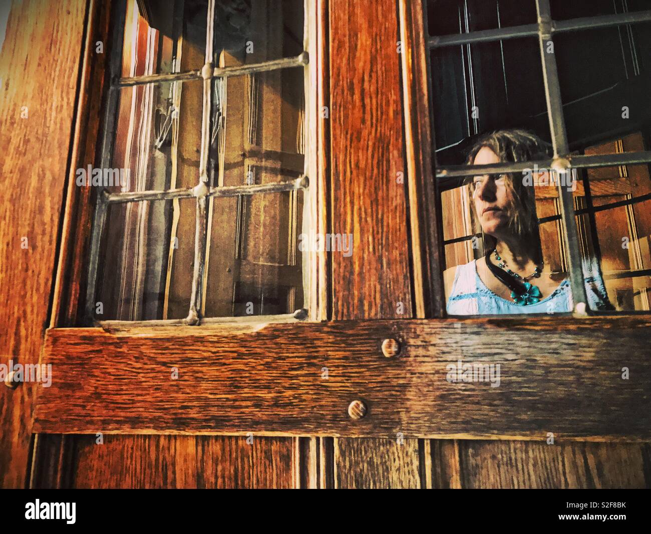 A woman appears as a ghostly reflection in the glass of an antique oak door Stock Photo