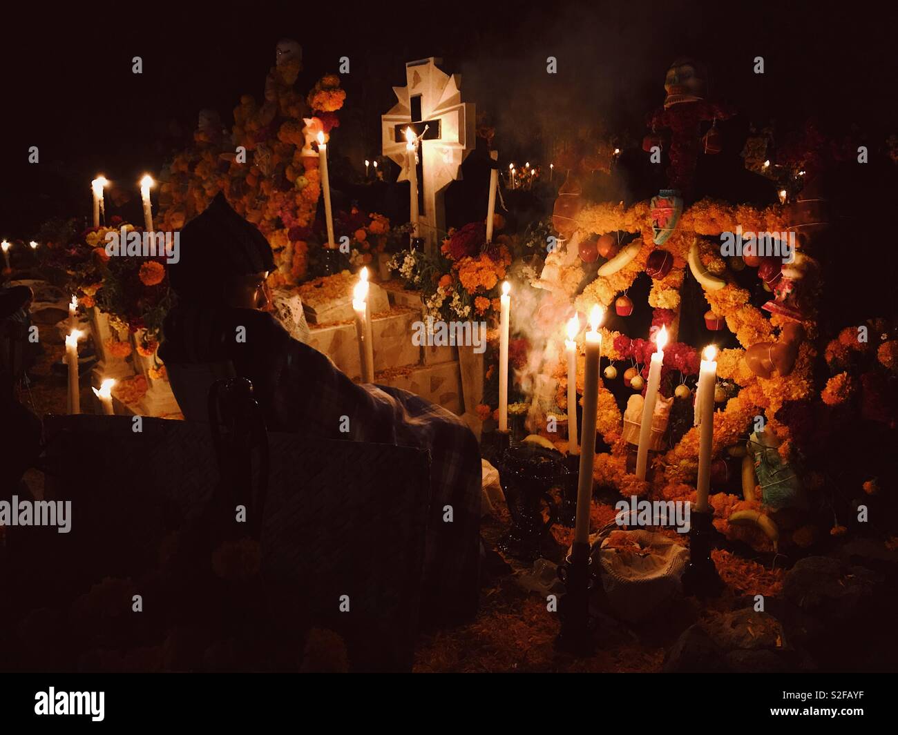 Boy and the Dead. Boy sitting near altar at the cemetery during Día de Muertos festival in Janítzio, Michoacan, Mexico. 1st of November 2017 Stock Photo