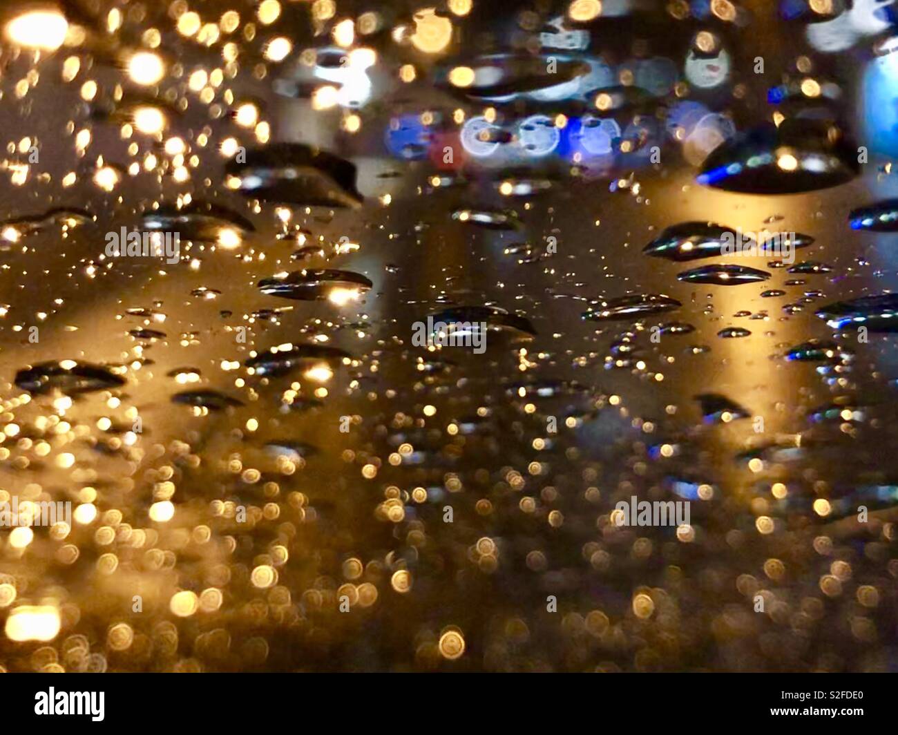 Rain drops on a window with street scene behind - Smartphone Captured Stock Image