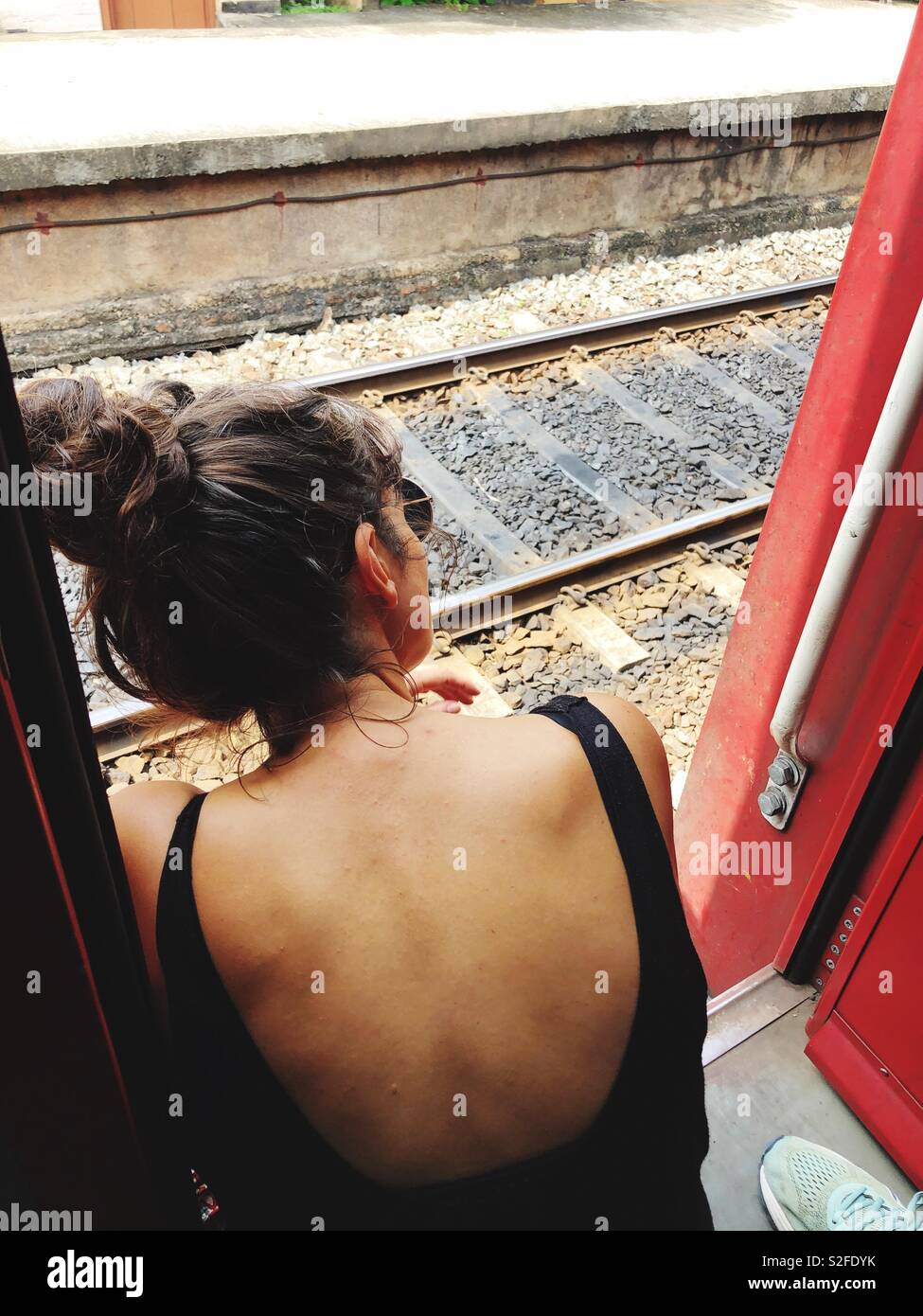 Woman sitting in open train door Stock Photo