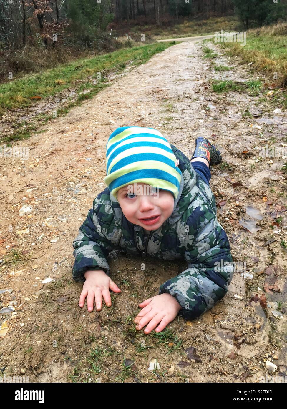 Two year old boy who has fallen over on a muddy footpath, Hampshire, England, United Kingdom. Stock Photo