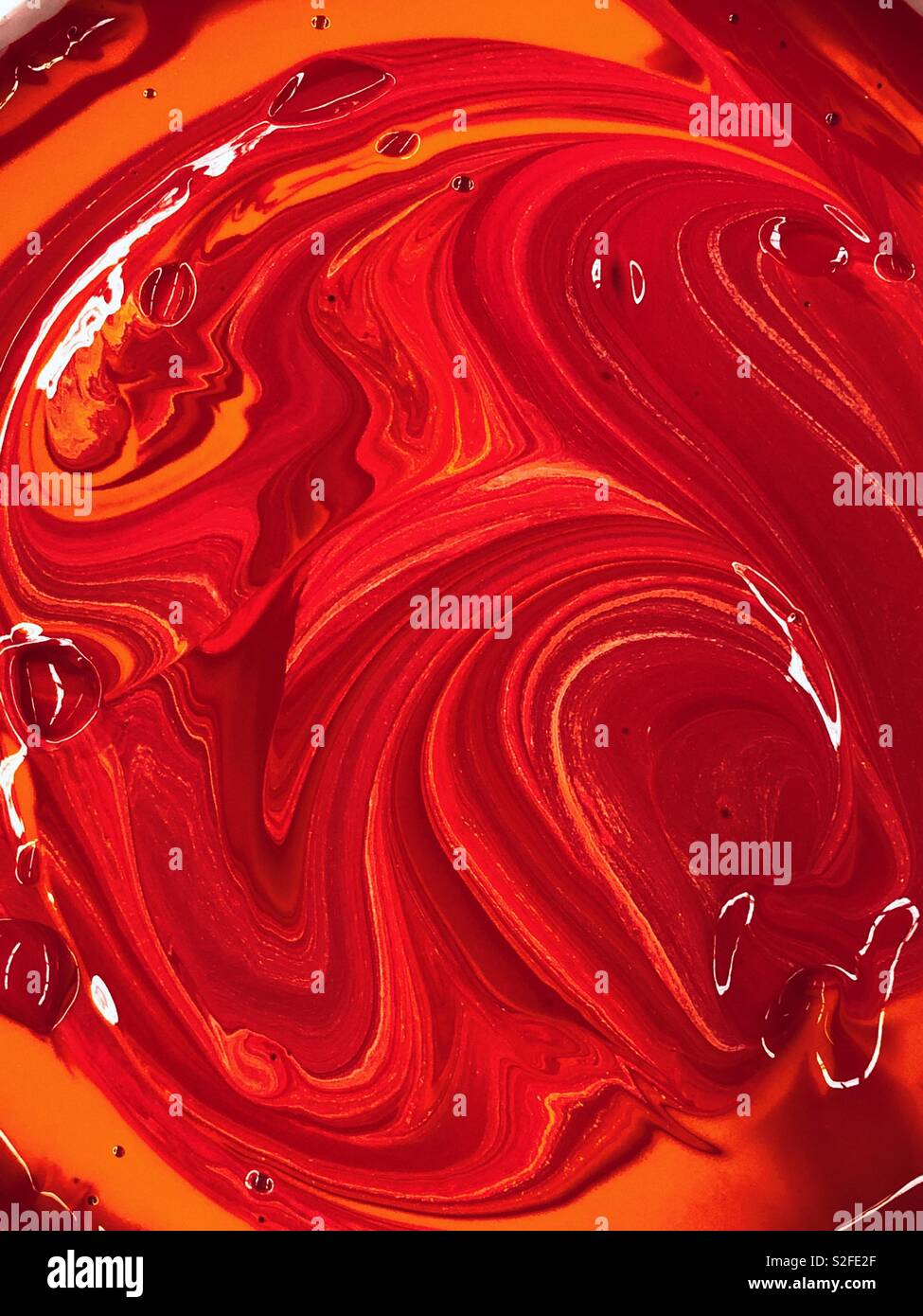 Abstract swirls of orange and yellow paint - living coral color of 2019 by Pantone Stock Photo