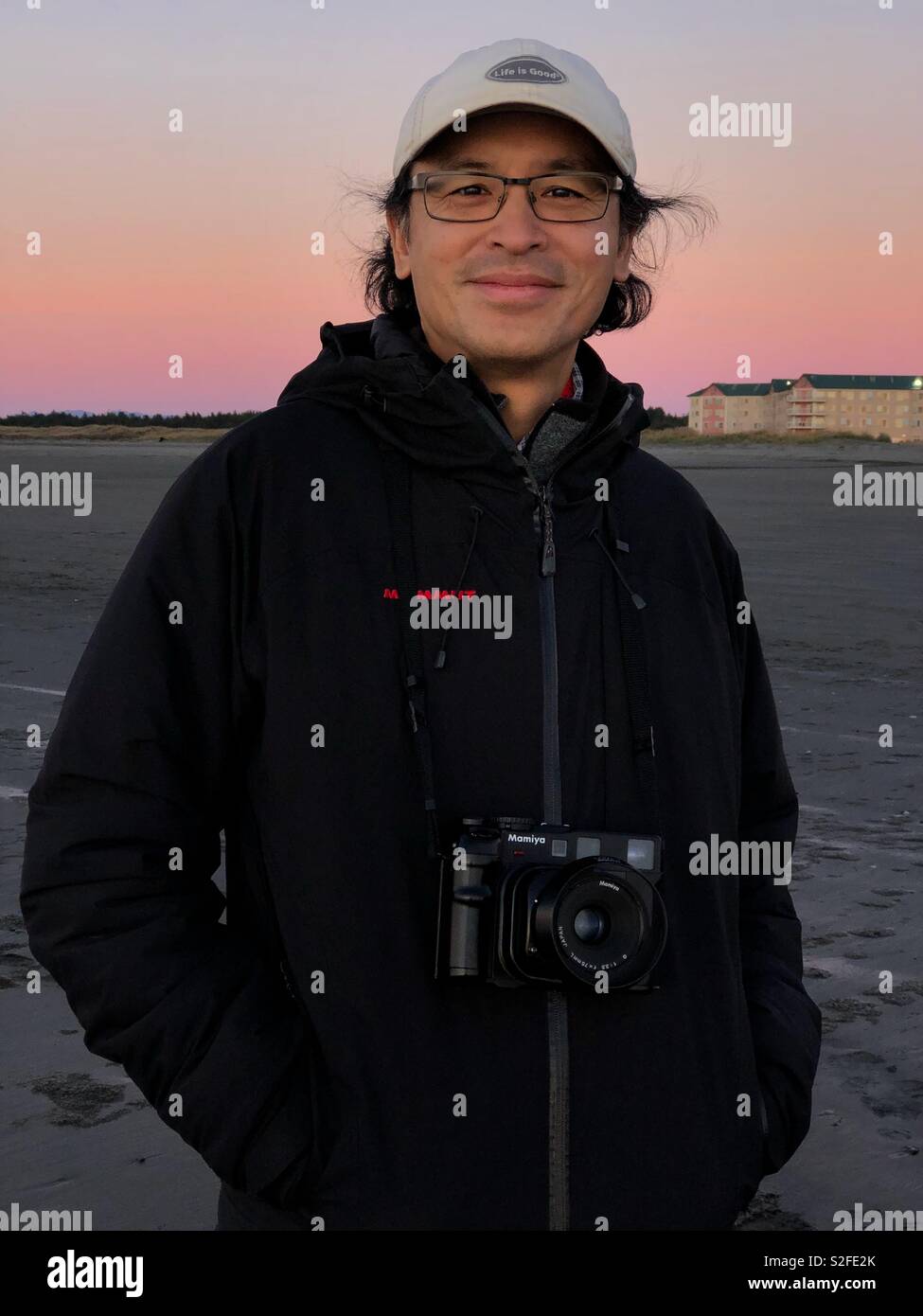 Smiling Asian man at sunset with medium format vintage Mamiya film camera Stock Photo